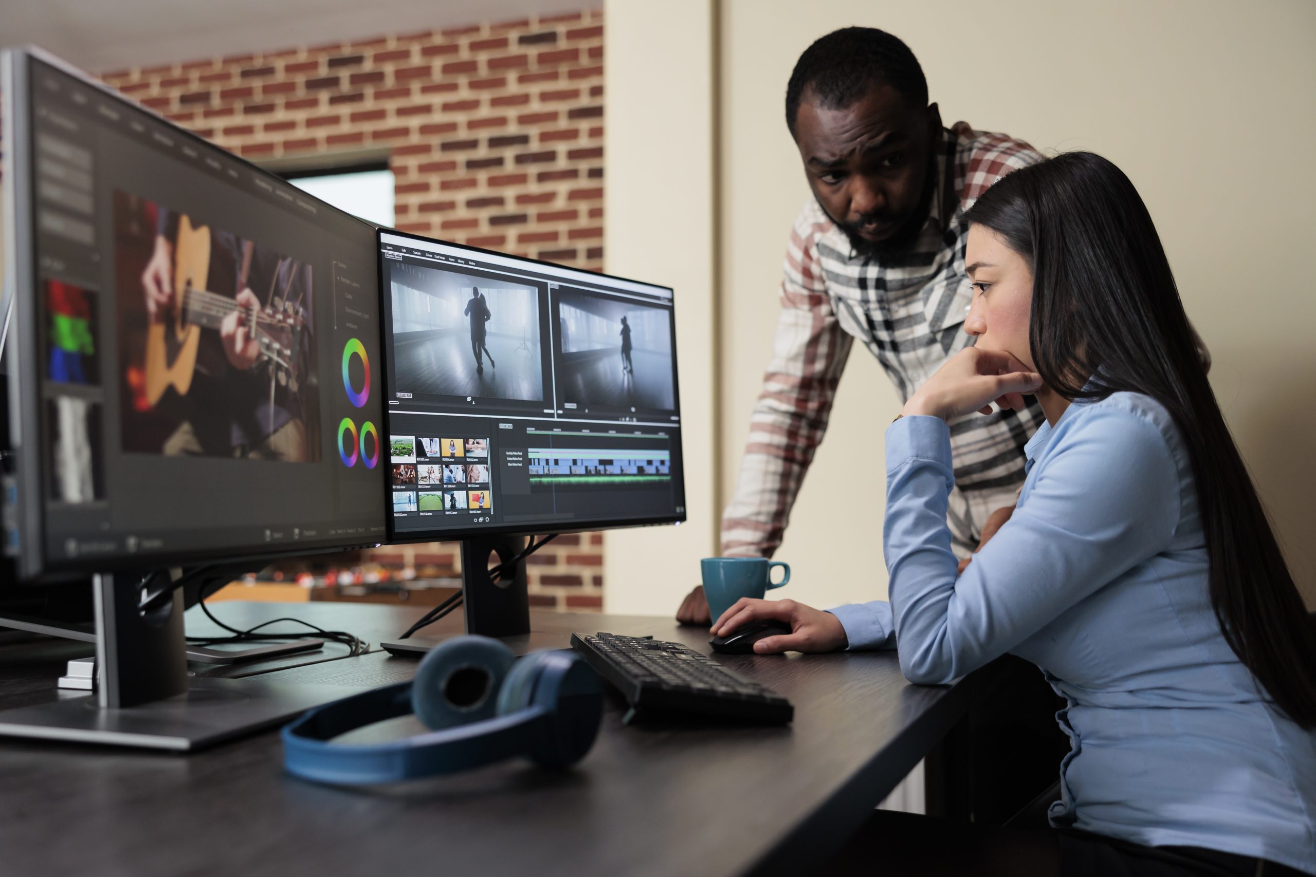 Post production house employee talking with coworker about footage quality. Professional movie editor sitting at desk while improving film frames using advanced specialized software.